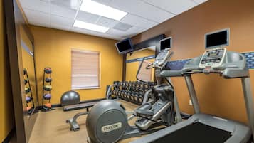 A gym with treadmills, an elliptical, a stationary bike, and a set of dumbbells.
