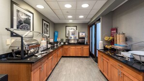 Una cocina de hotel con un sistema de bufé, que incluye una estación de café, un dispensador de agua y diversos alimentos.