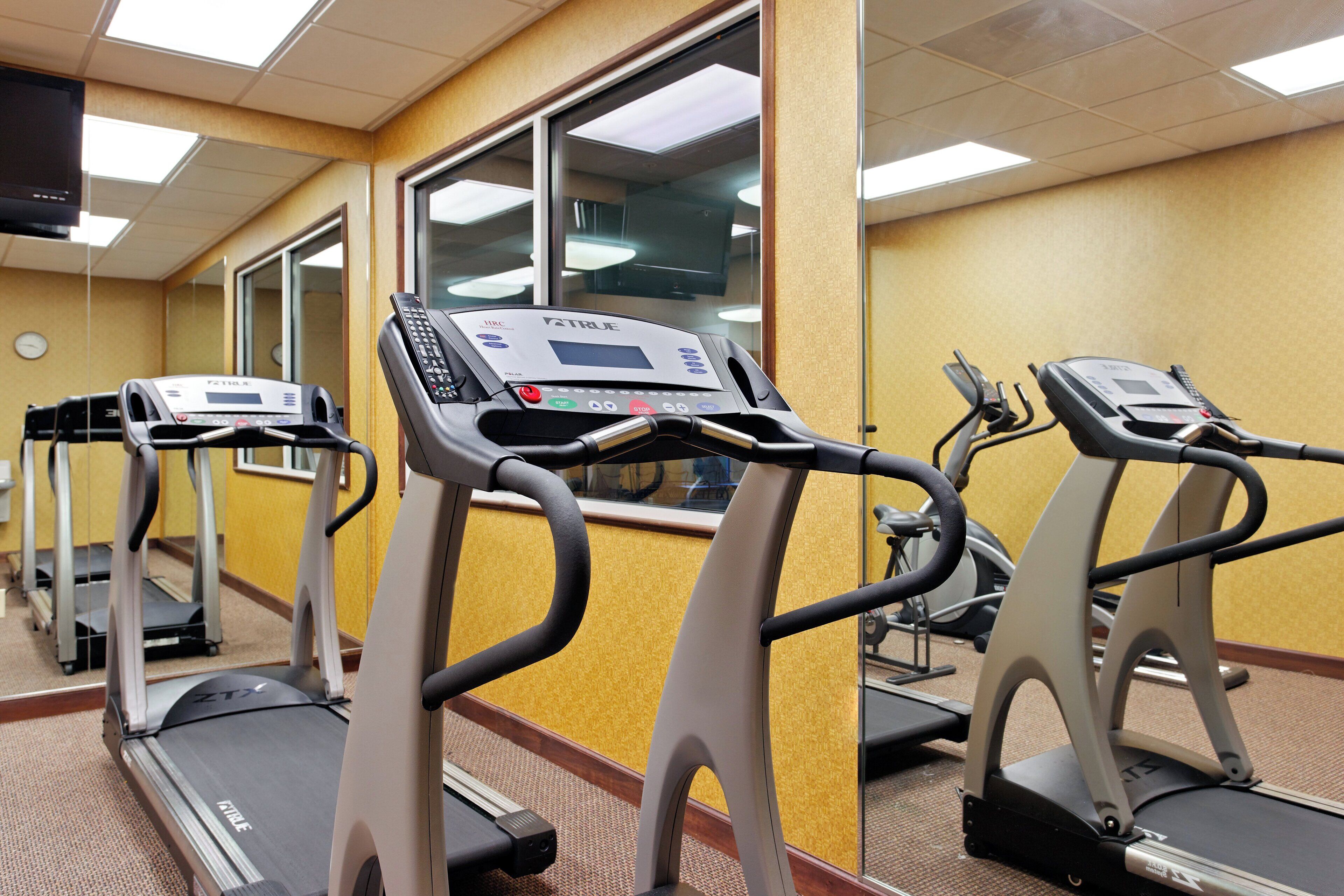 A gym with treadmills, a control panel, and a window.