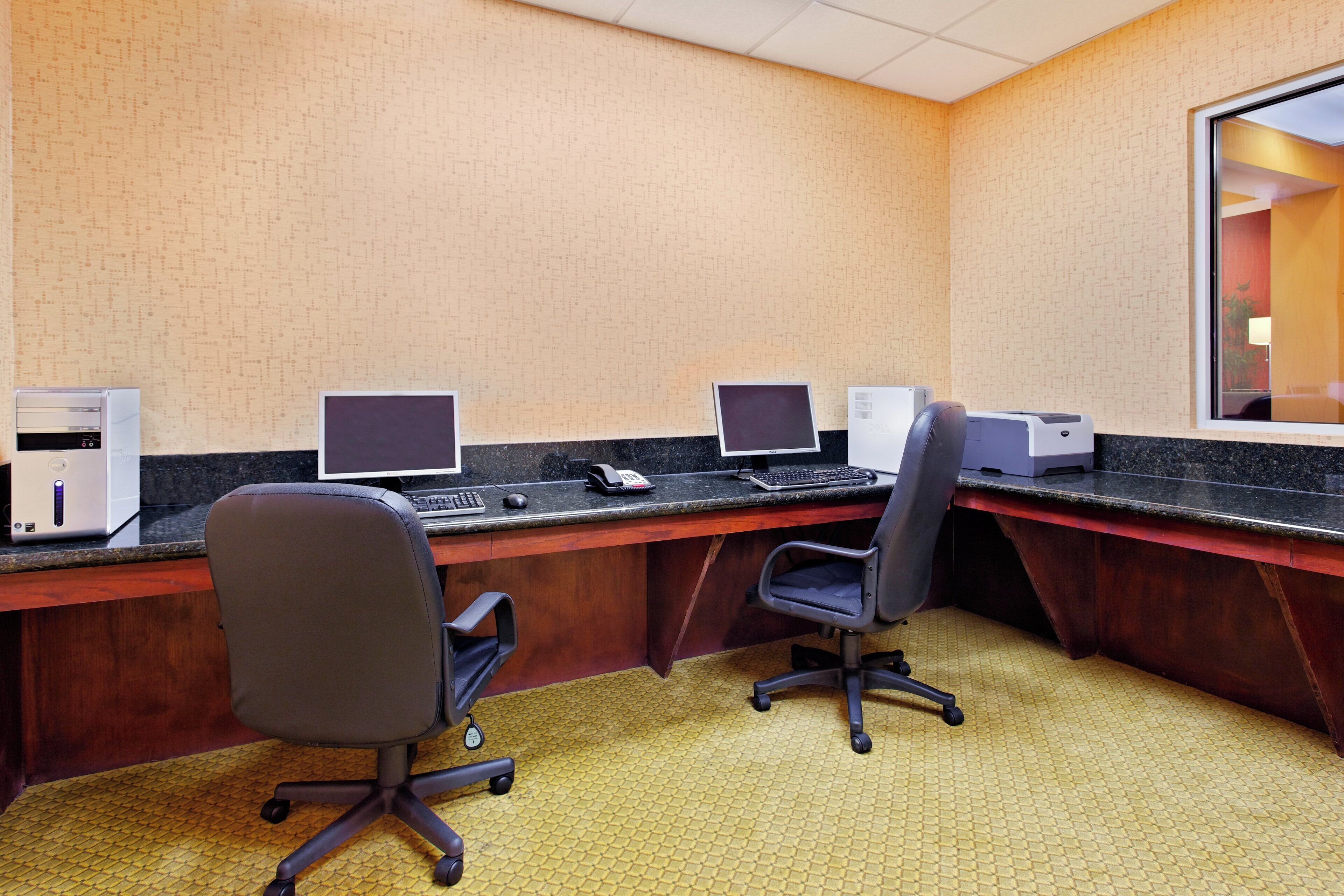 A conference room with two desks, each equipped with a computer, a phone, and a keyboard.
