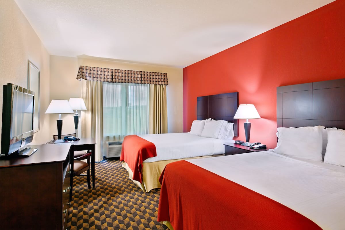 A hotel room with two beds, a desk with a computer, and a TV.