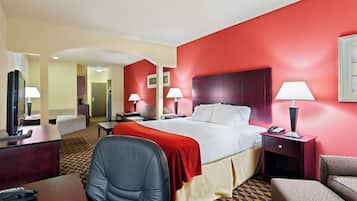 A hotel room with a large bed, two bedside tables with lamps, a desk with a telephone, a chair, and a patterned carpet.