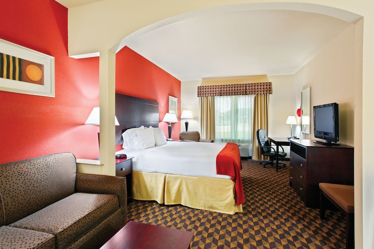 A hotel room with a bed, desk, chair, and a television.