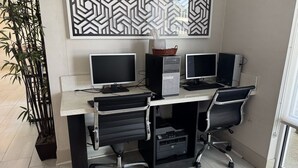 Una estación de trabajo con dos monitores, un ordenador de escritorio, dos sillas de oficina e impresora.