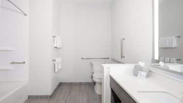 A modern bathroom with a toilet, a shower, and a sink with a mirror.