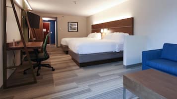 A hotel room with two beds, a desk with a chair, a blue sofa, and a wooden nightstand.