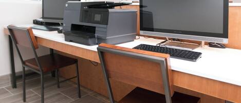A workspace with two desktop computers, a printer, and a keyboard on a white desk.