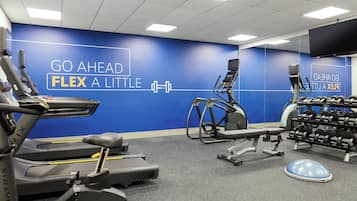 A gym with treadmills, elliptical machines, and a weight rack.