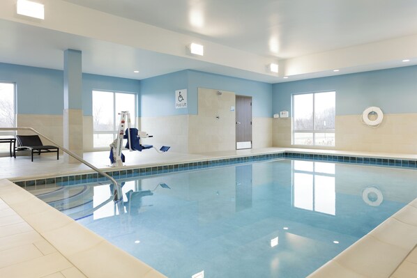 An indoor swimming pool with clear blue water, a pool lift, and a lifeguard chair. - Holiday Inn Express Hotel & Suites Cincinnati Se Newport by IHG (Bellevue)