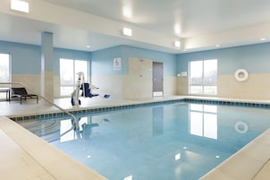 Piscina interna com água azul cristalina, elevador de piscina e cadeira de salva-vidas.