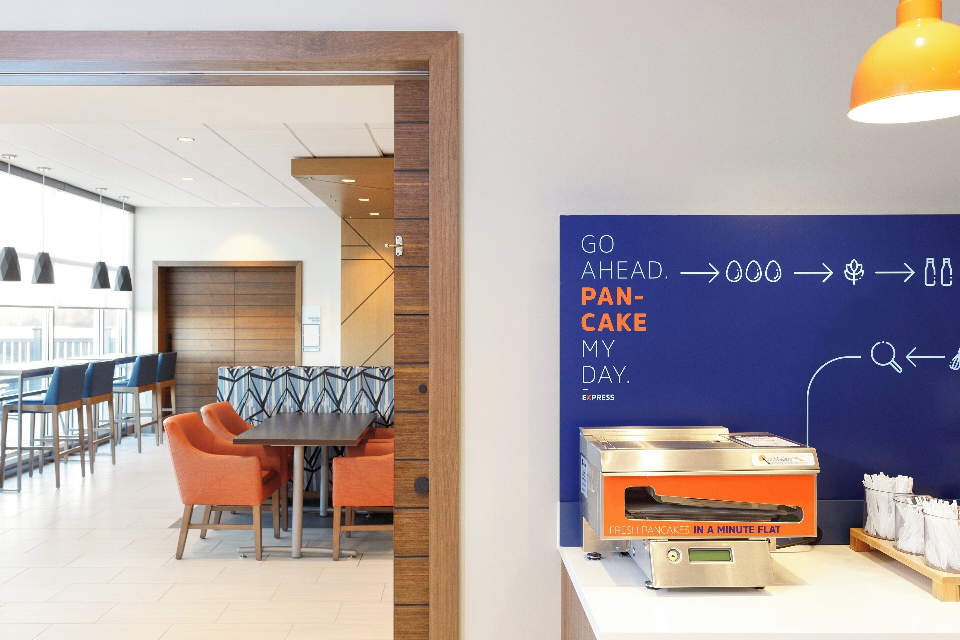 Un espace repas moderne avec un coin pour le petit-déjeuner et un mur bleu orné d’un texte.
