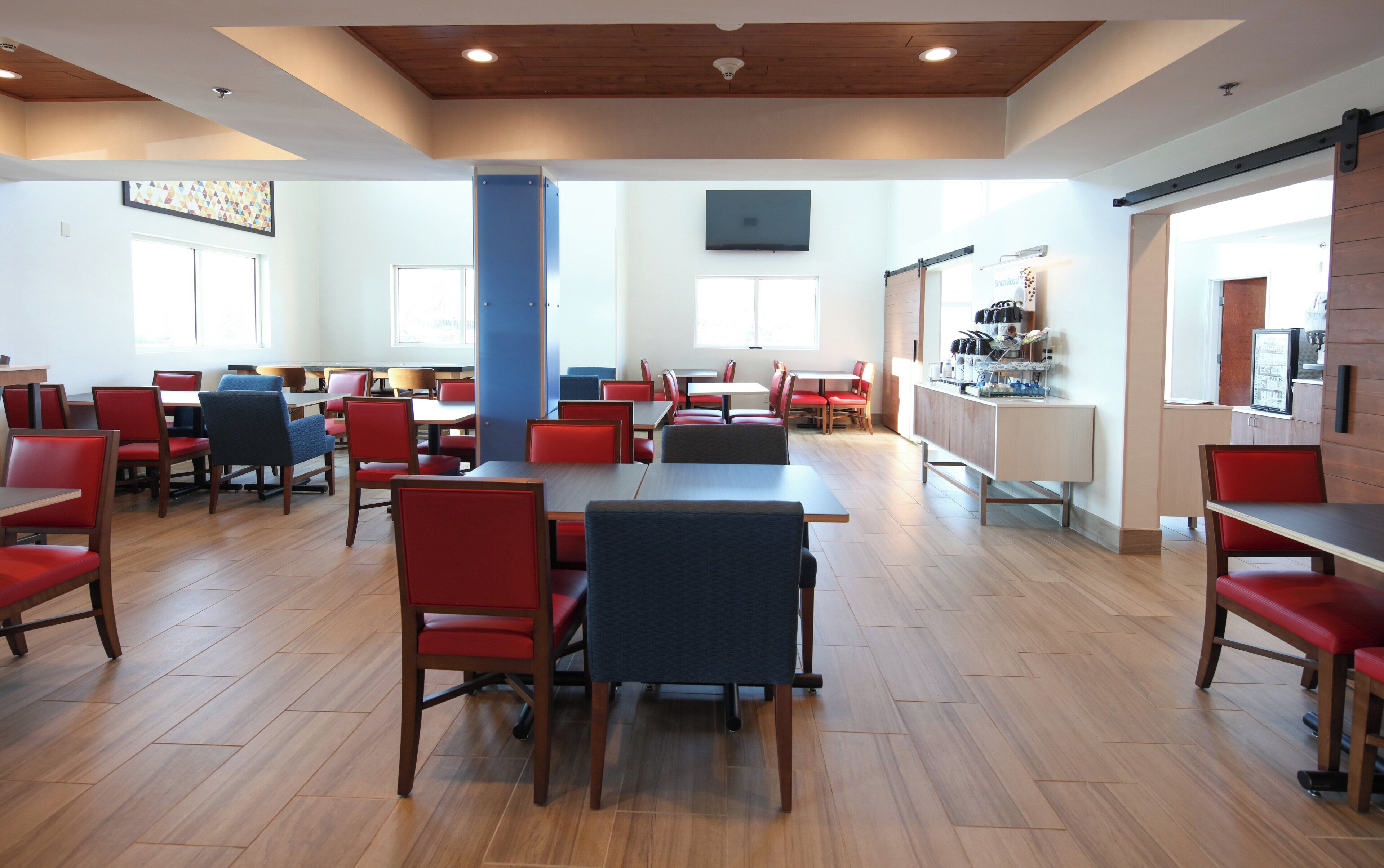 A spacious dining area with multiple tables and chairs, a central pillar, and a counter with various items.