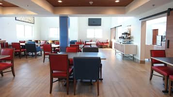 A spacious dining area with multiple tables and chairs, a central pillar, and a counter with various items.
