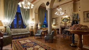 Une vaste pièce comprenant un canapé, des fauteuils, un tapis à motifs et un lustre.