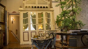 Une pièce au décor traditionnel, avec un tapis à motifs, une table sur laquelle est disposée une sélection d’objets et une plante décorative.