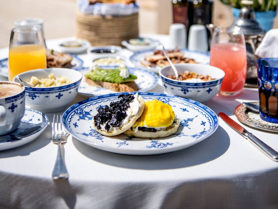 A table set with breakfast items including eggs, toast, and beverages, overlooking a scenic coastal view.