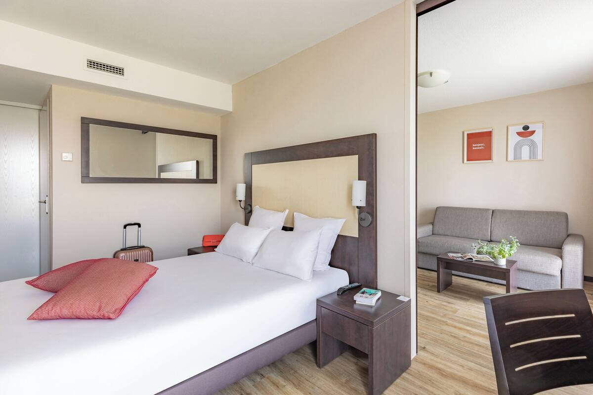 A hotel room with a large bed, a bedside table, a nightstand, a sofa, and a coffee table.