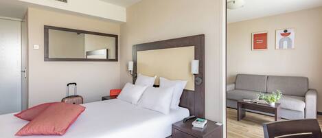 Habitación de hotel con una cama grande, una mesita de noche, un sofá y una mesa de centro.