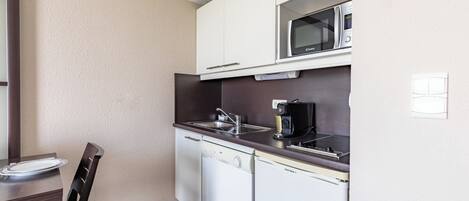 Una cocina compacta equipada con microondas, lavavajillas y cafetera.