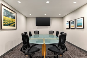 A conference room with a glass table, black chairs, a flat-screen TV, and framed pictures on the walls. - Candlewood Suites Oak Harbor by IHG (Oak Harbor)