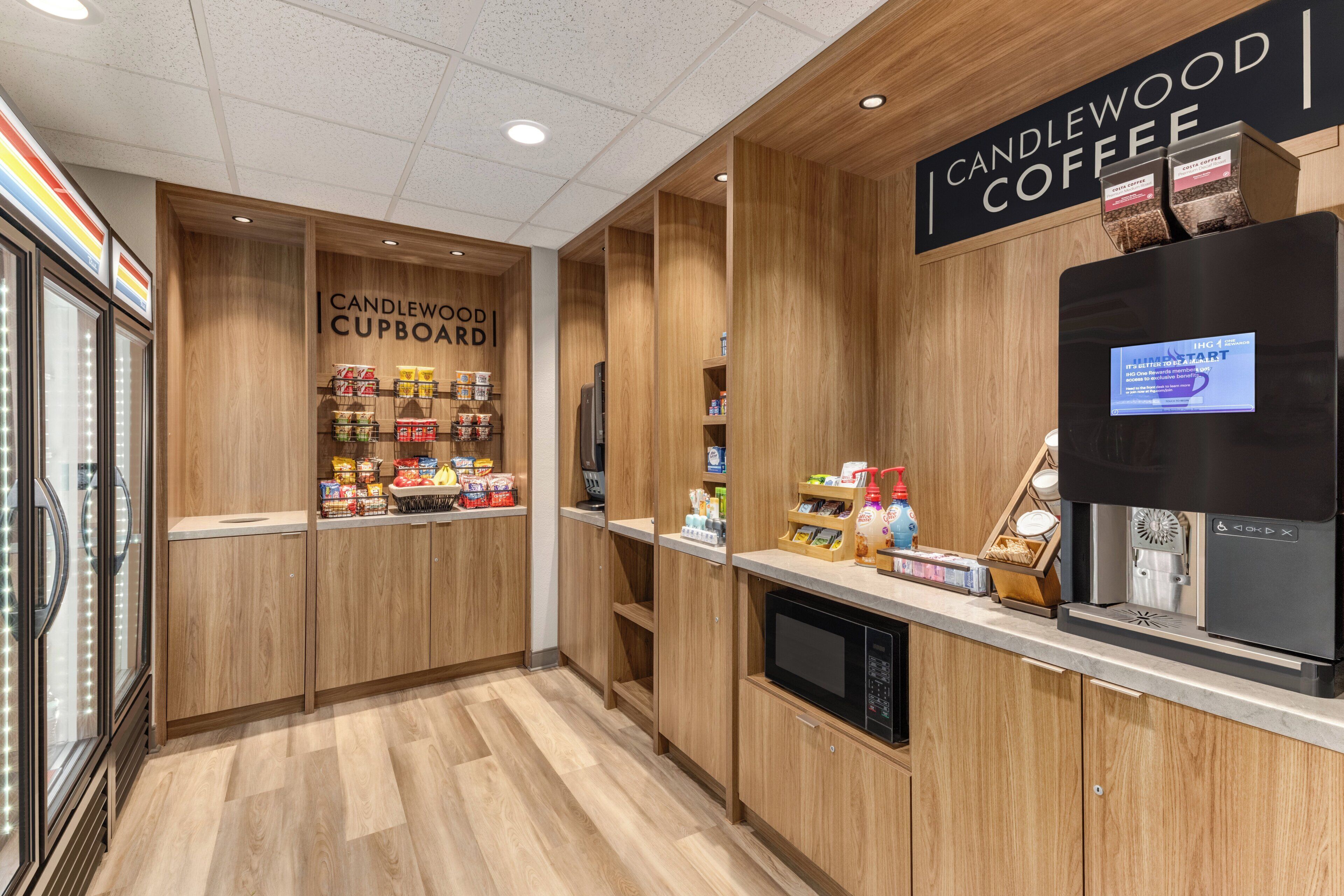 Una cafetería con un letrero que dice 'CANDLEWOOD COFFEE' y un refrigerador exhibiendo productos.