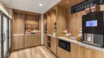 Una cafetería con un letrero que dice 'CANDLEWOOD COFFEE' y un refrigerador exhibiendo productos.