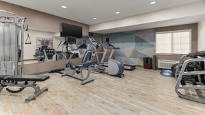 A gym with exercise equipment, a mirror, and a window.