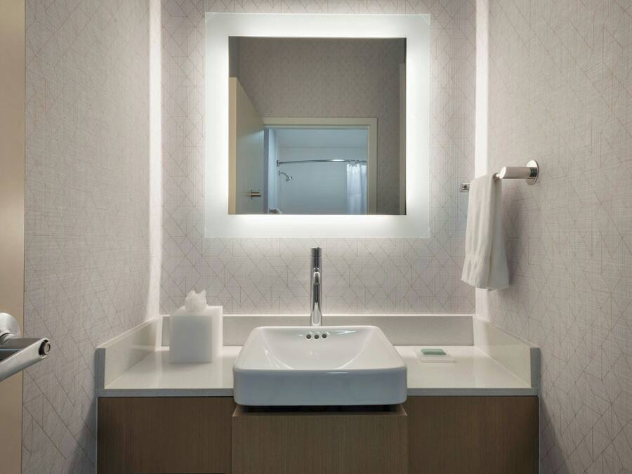 A modern bathroom with a rectangular mirror, a white sink, and a towel rack.