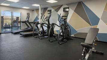 A gym with treadmills, elliptical machines, and a weight bench.