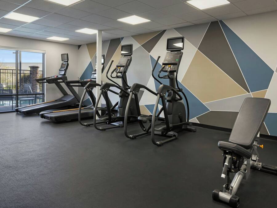 A gym with treadmills, elliptical machines, and a weight bench.