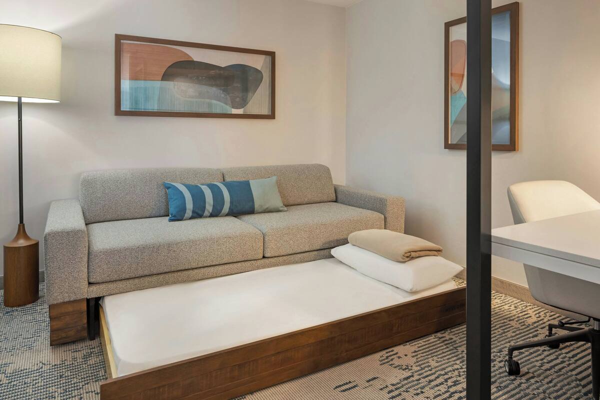 Une chambre d’hôtel moderne équipée d’un canapé, d’un lit simple, d’un bureau et d’une chaise.