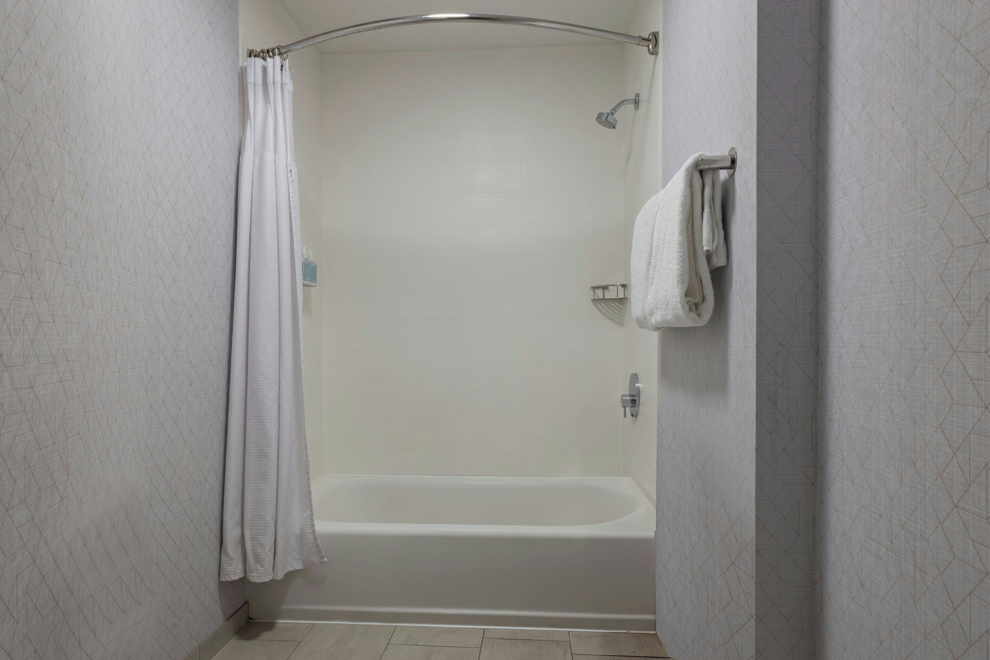A bathroom with a shower, a bathtub, and a towel rack.