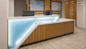 A reception desk with a wooden finish and a lighted blue accent. There are two computer monitors on the desk, and a sign indicating the location as Marriott Bonvoy.