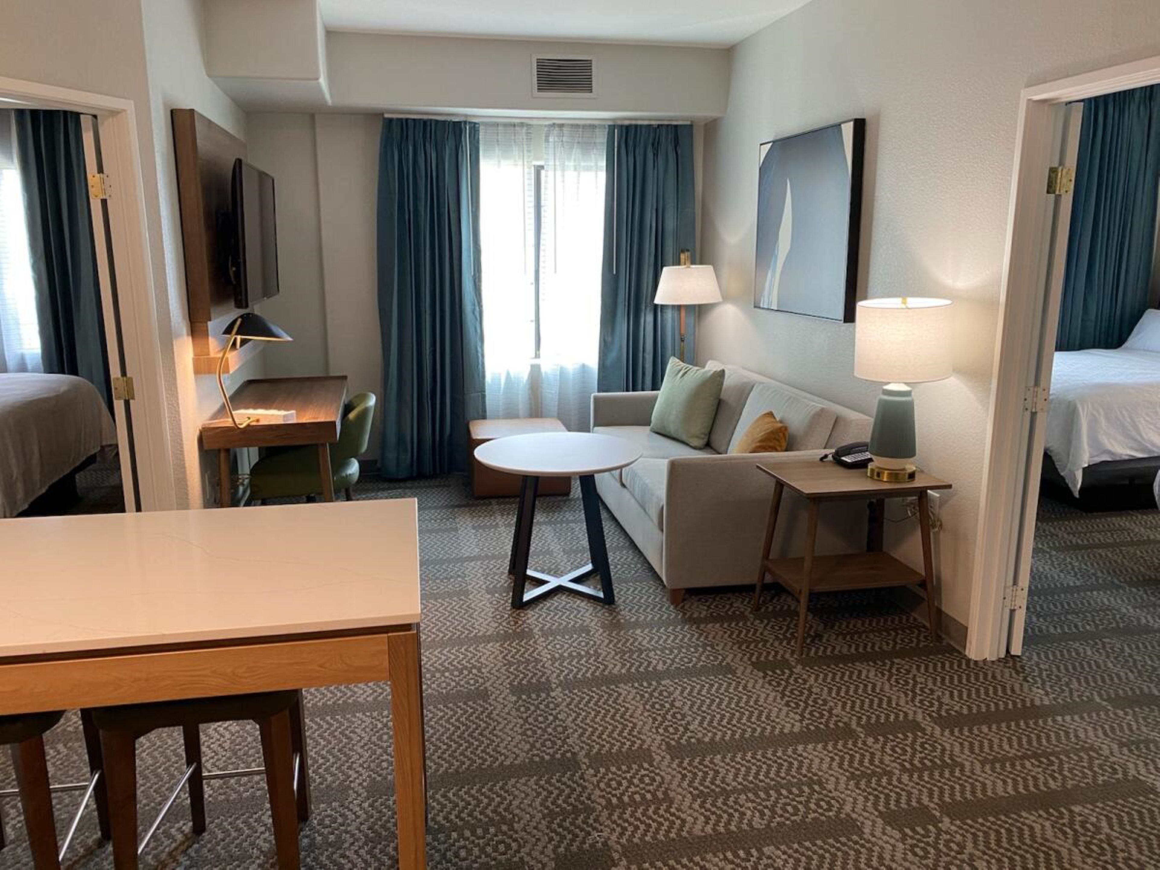 Una habitación de hotel con una cama, un sofá, una mesita, un escritorio y una silla.