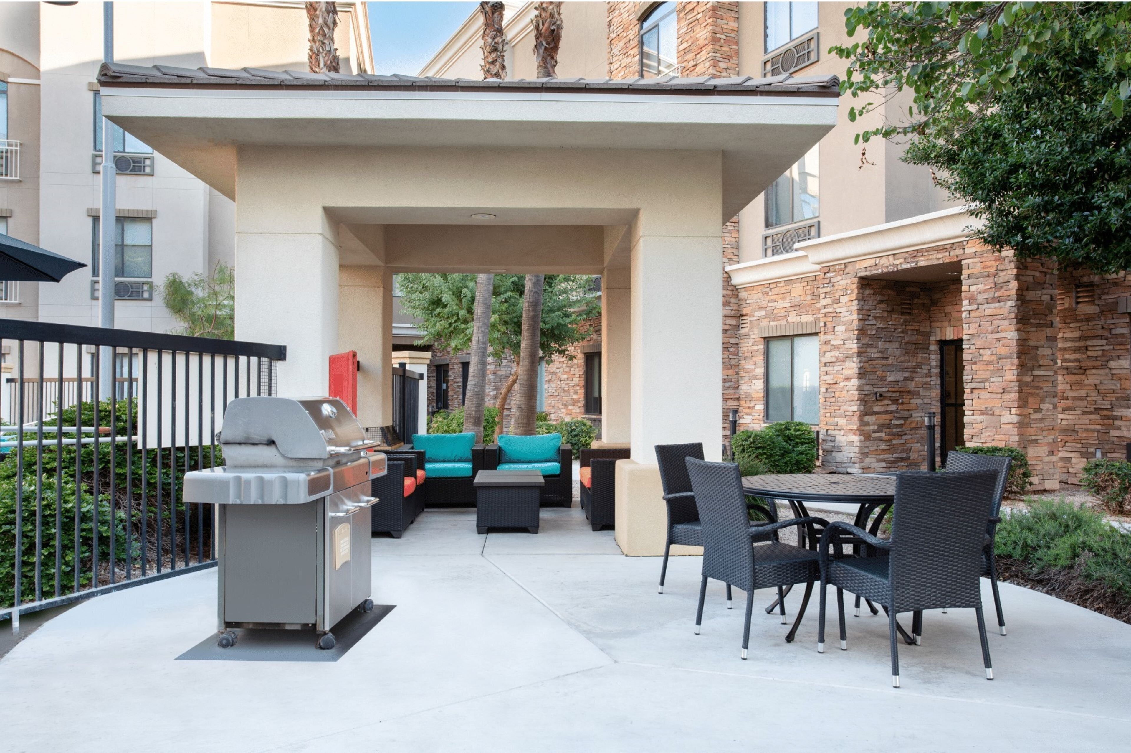 Un espace extérieur aménagé en terrasse, avec un barbecue, des sièges et une allée couverte.