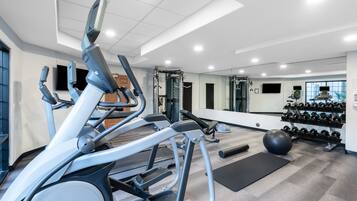Un gimnasio moderno con cintas de correr, máquinas de pesas y una variedad de mancuernas.