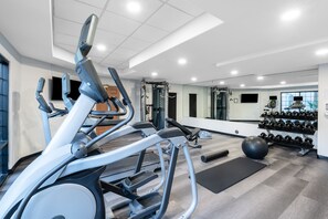 Une salle de sport moderne équipée de tapis de course, d’appareils de musculation et d’une variété d’haltères.