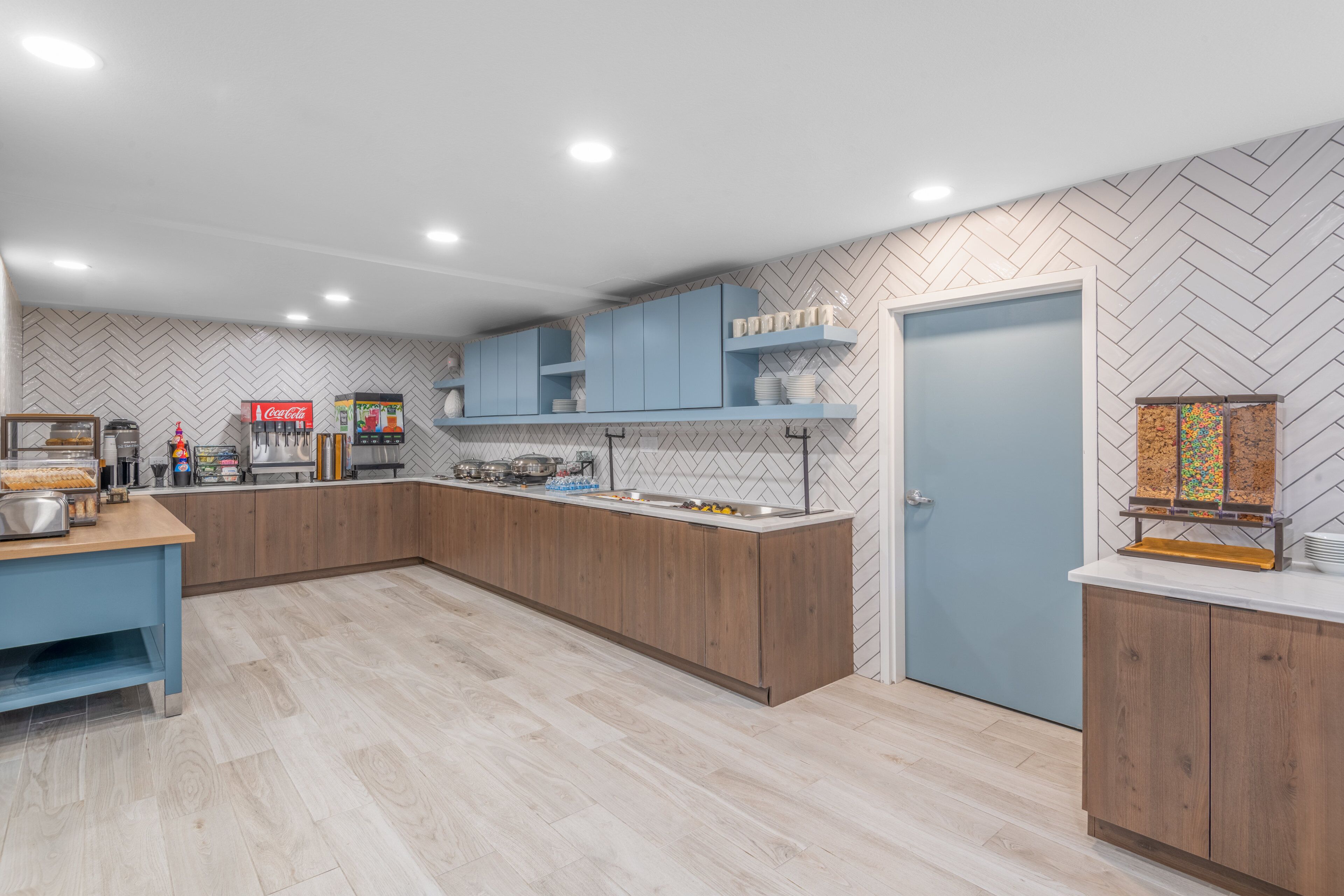 A modern kitchen with wooden cabinets, a built-in coffee station, and a herringbone-patterned backsplash.
