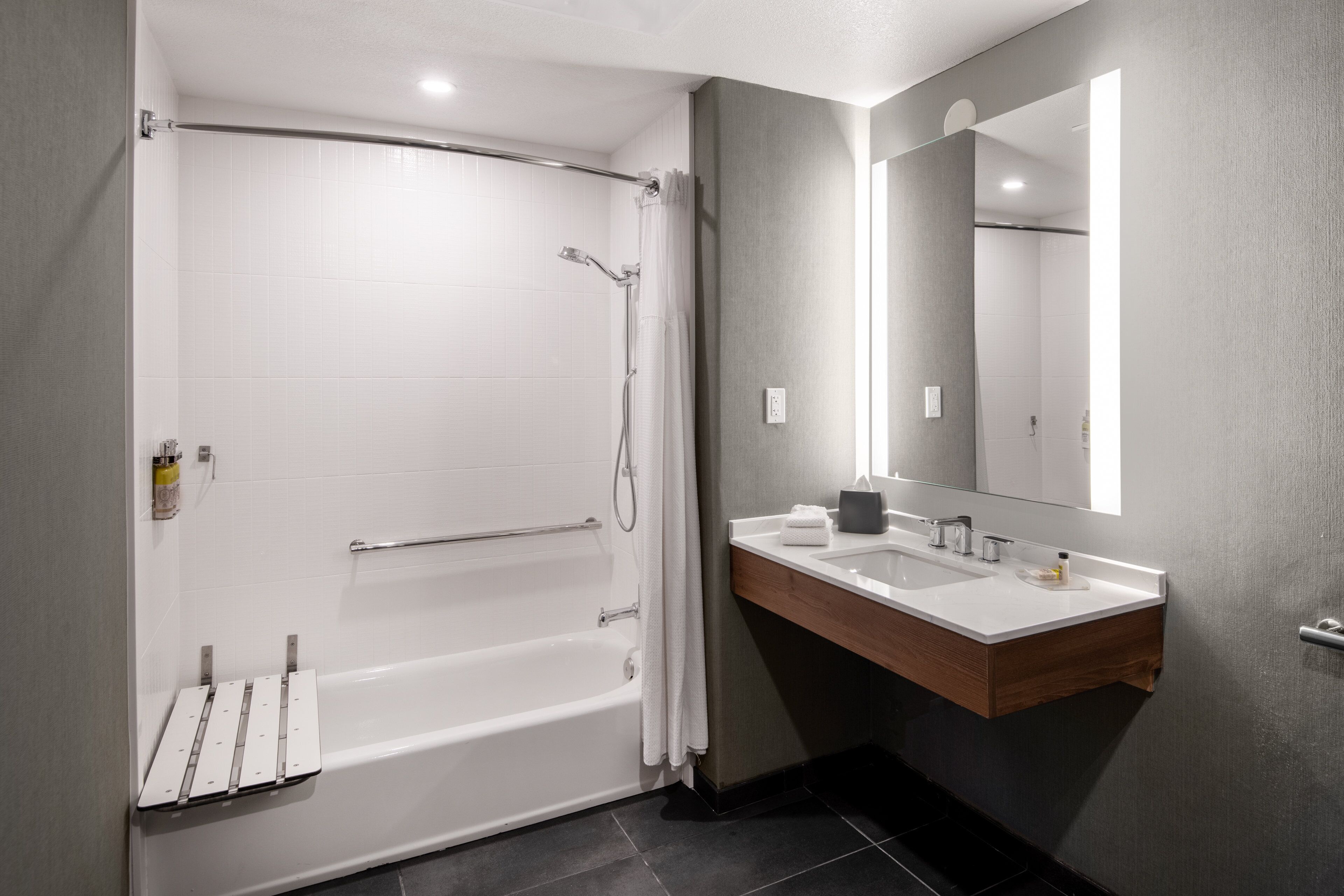 A modern bathroom with a bathtub, a vanity with a mirror, and a shower area.