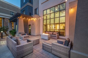 An outdoor patio with wicker furniture, a fire pit, and string lights. - Staybridge Suites Phoenix - Glendale Sports Dist by IHG (Glendale)