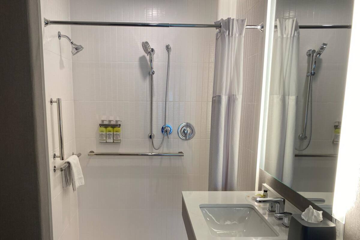 A modern bathroom with a walk-in shower, a vanity with a sink, and a mirror.