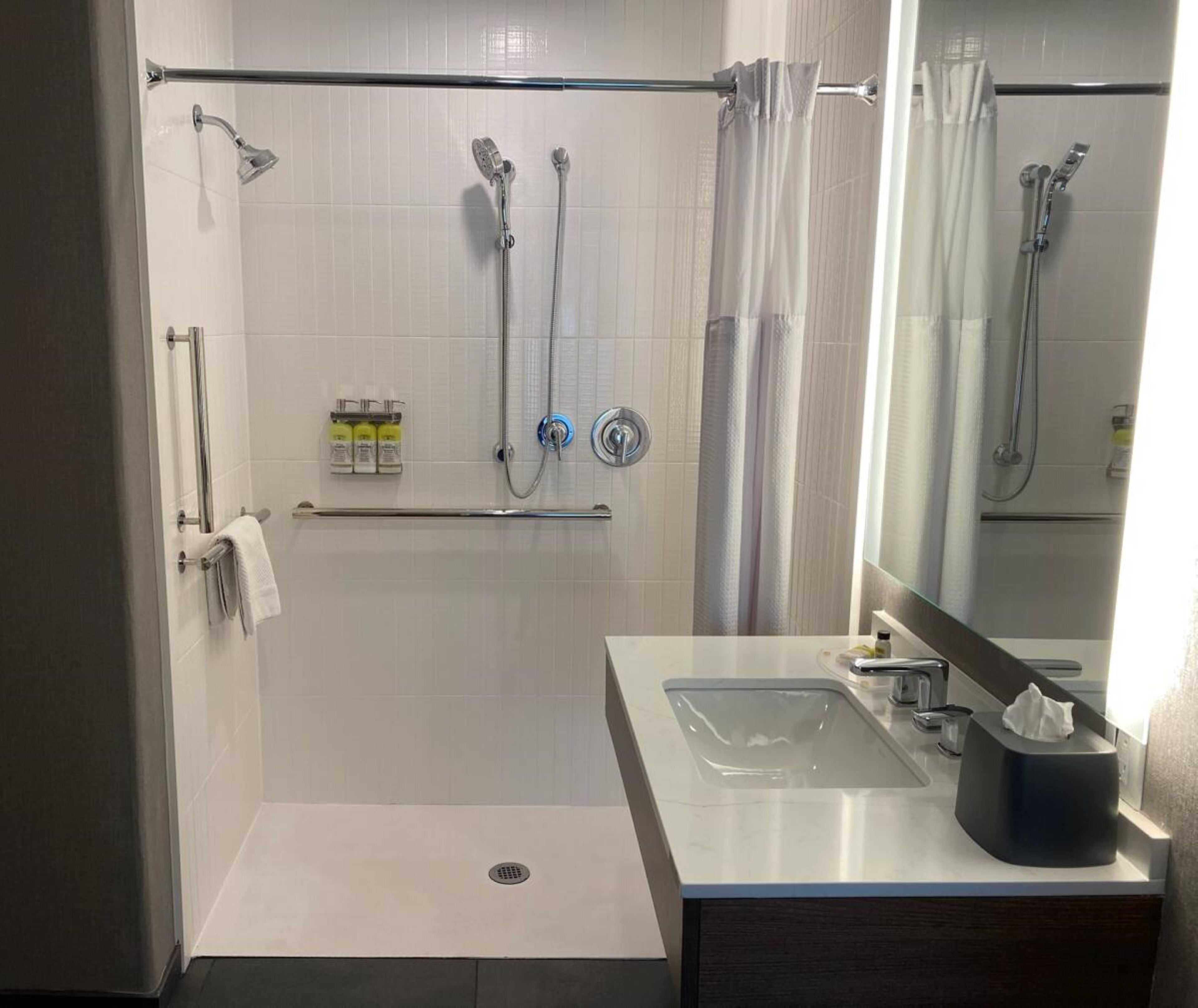 A modern bathroom with a walk-in shower, a vanity with a sink, and a mirror.