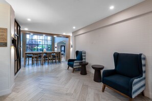 A modern interior with a dining area, two armchairs, and a small table. - Staybridge Suites Phoenix - Glendale Sports Dist by IHG (Glendale)