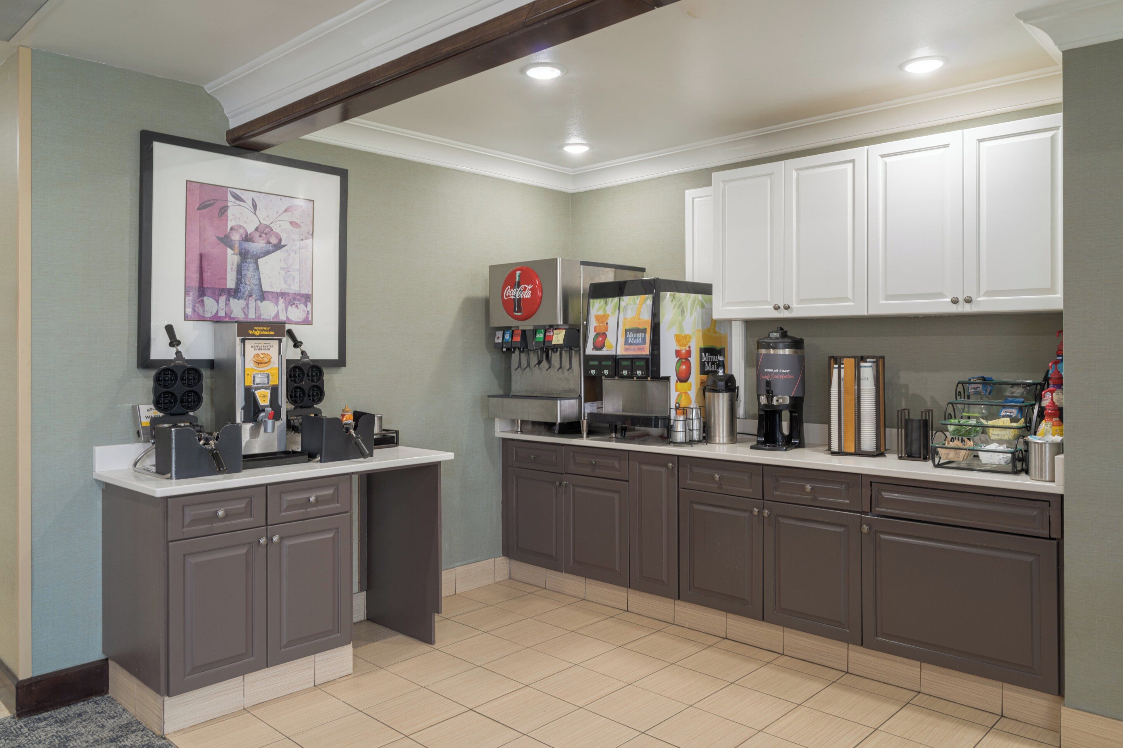 Een kitchenette met een koffiehoek, een Coca-Cola koelkast en een magnetron.
