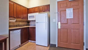 A compact kitchen with wooden cabinets, a white refrigerator, and a dishwasher.