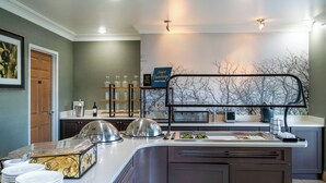 A buffet setup with a glass display case, a sign, and a microwave. - Staybridge Suites Augusta by IHG (Augusta)