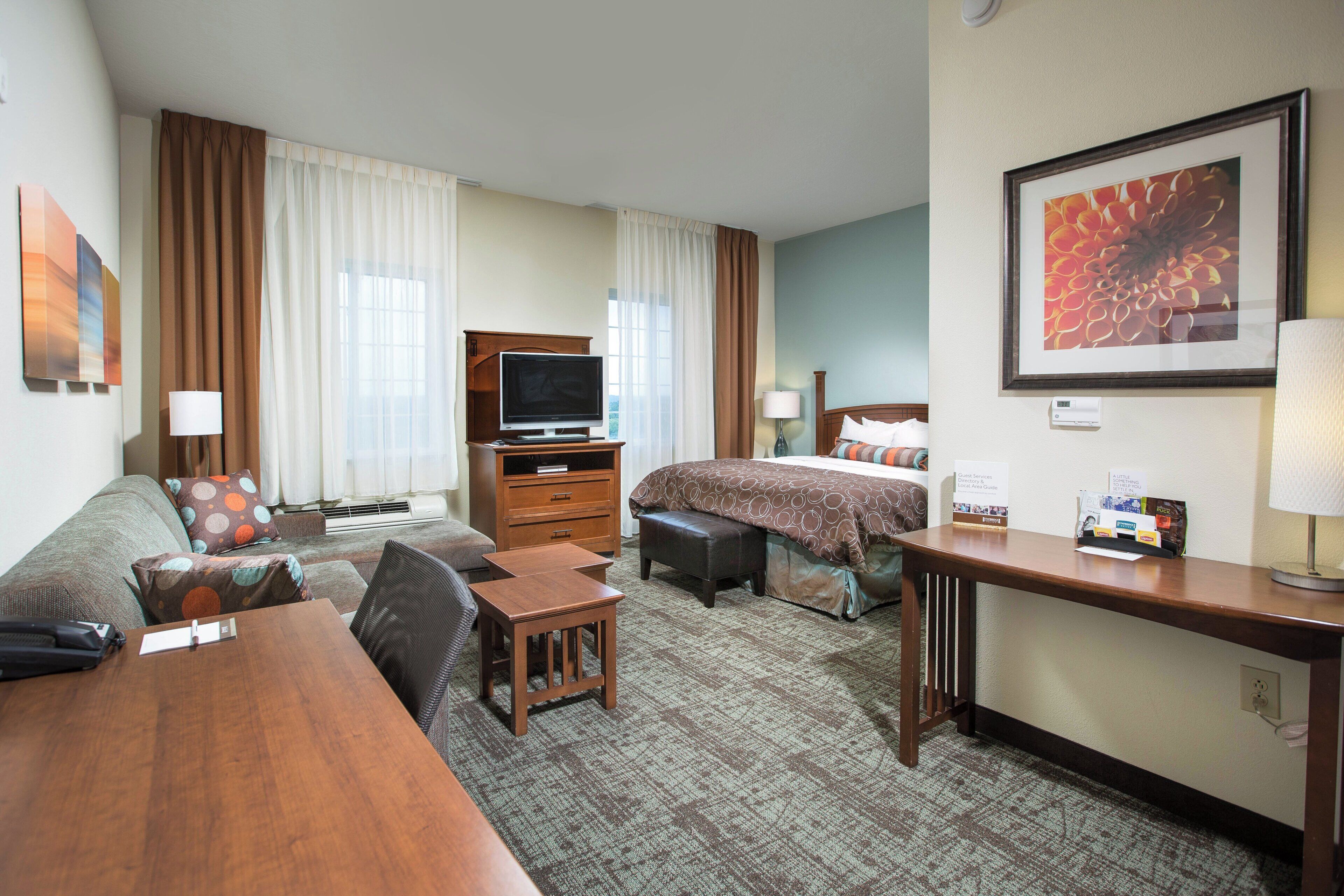 Une chambre d’hôtel comprenant un lit, un bureau, une télévision, un canapé et une petite table.