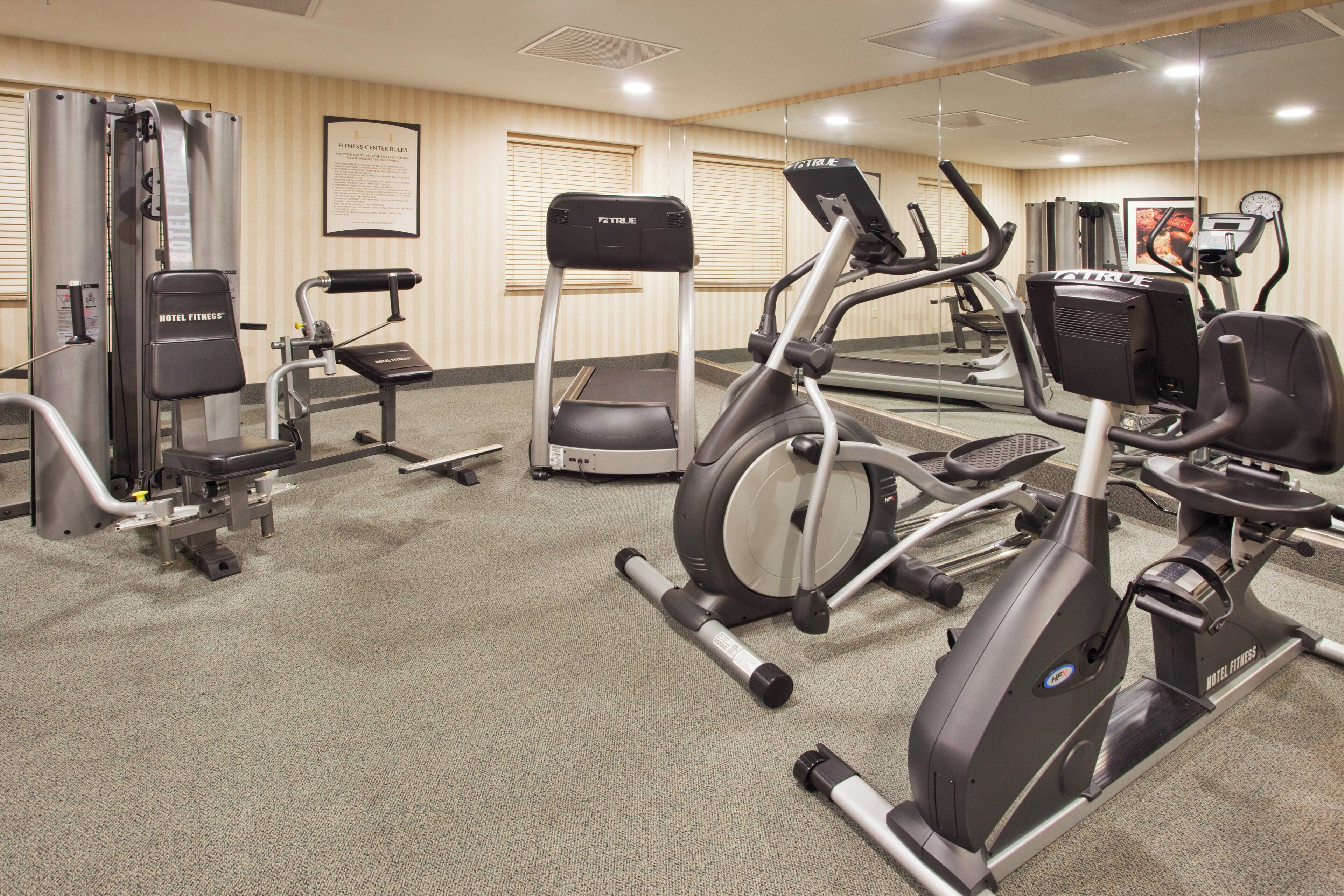 A hotel fitness center with various exercise equipment including treadmills, elliptical machines, and weight machines.