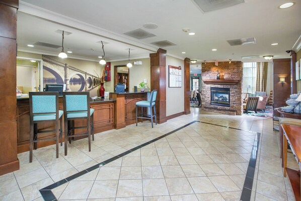 A hotel lobby with a reception desk, seating area, and a fireplace. - Staybridge Suites Augusta by IHG (Augusta)