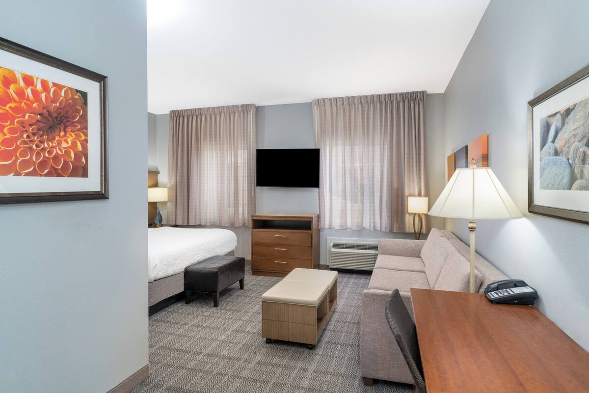 Une chambre d’hôtel avec un lit, un canapé, un bureau, une télévision et une lampe.